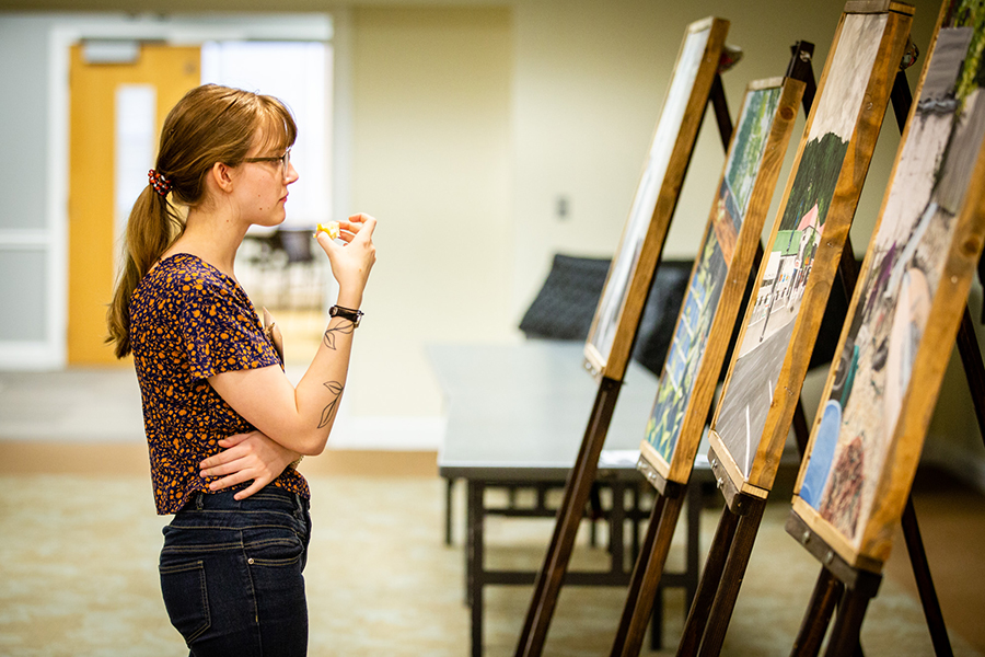 A student takes in a series of paintings during last year's Celebration of Quality academic symposium. Students are invited to submit their academic work for presentation at the 2020 Celebration of Quality, which takes place April 17. (Photo by Brandon Bland/Northwest Missouri State University)