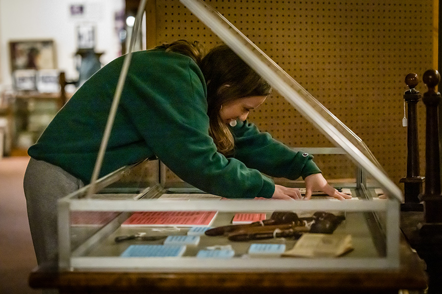 Northwest student Vivian King arranges artifacts in a display case to showcase research and items related to the history of the Daughters of the American Revolution. (Photo by Lilly Cook/Northwest Missouri State University)