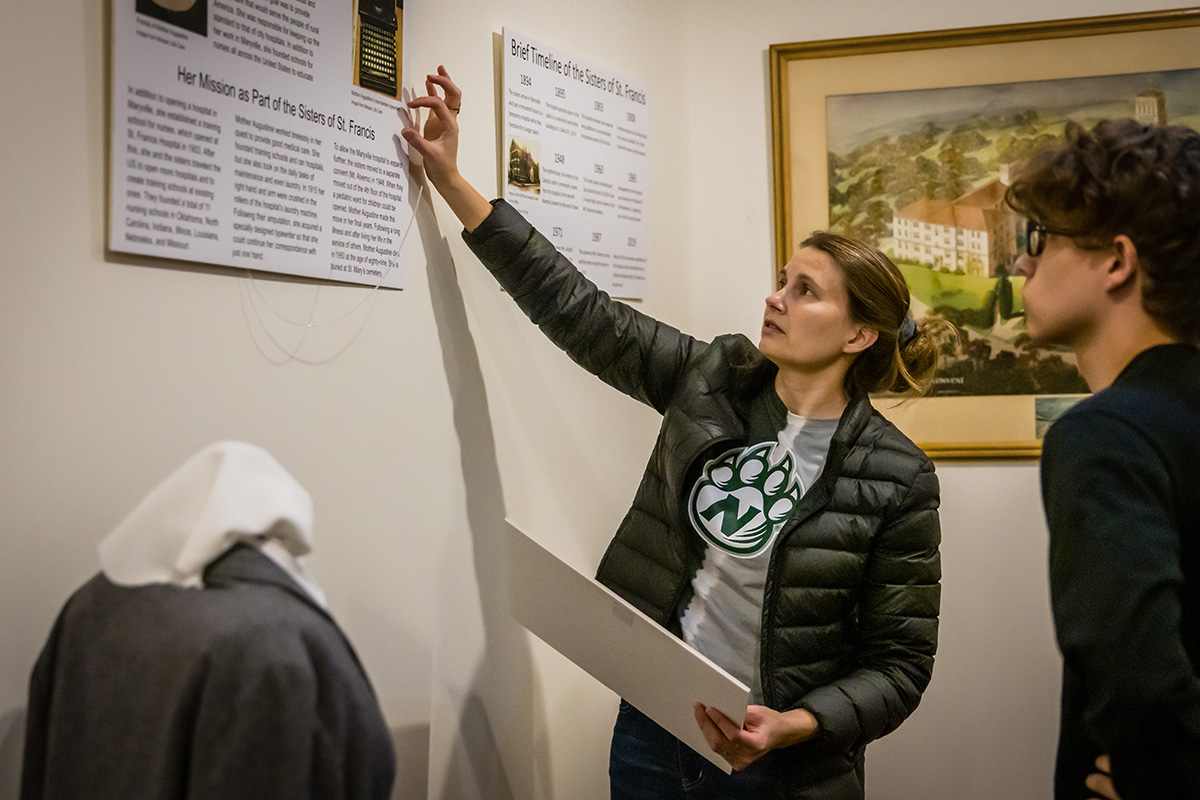 Dr. Elyssa Ford assists Northwest student William Edwards with a panel about the Sisters of St. Francis. (Photo by Lilly Cook/Northwest Missouri State University)