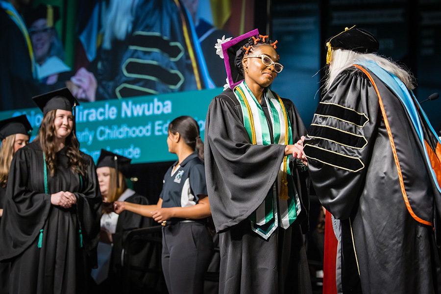 Obioma Nwuba, who graduated with a bachelor's degree in early childhood education, shakes the hand of Northwest Provost Dr. Jamie Hooyman during the University's commencement ceremonies. (Photo by Todd Weddle/Northwest Missouri State University)